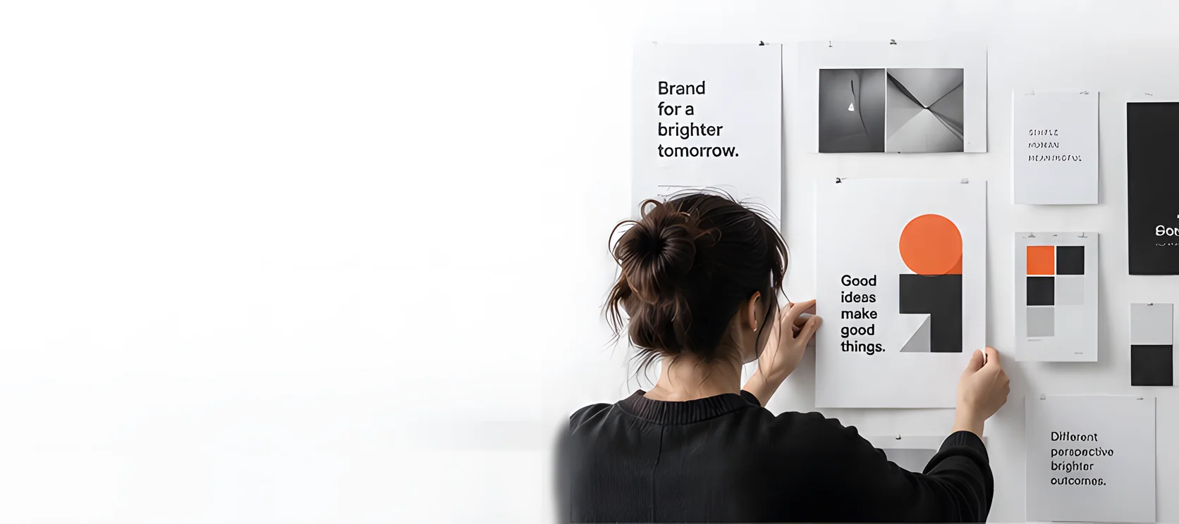 A graphic designer pinning printed concepts to a studio moodboard wall