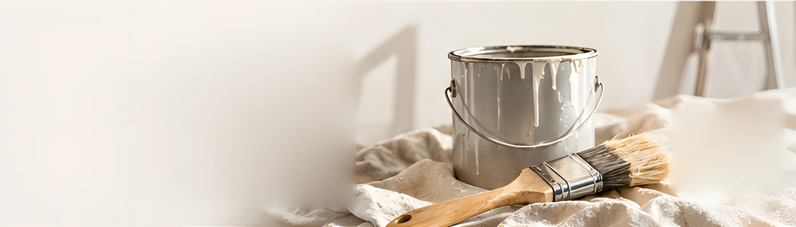 A paint can and two brushes on a dust sheet in a bright room